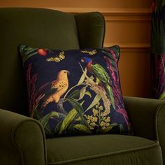 a green chair with a pillow on it and two colorful birds sitting on the pillows