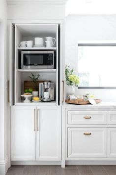 a kitchen with white cupboards and appliances on the counter top, along with wooden flooring