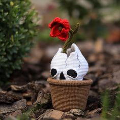 a knitted skull planter with a red flower in it