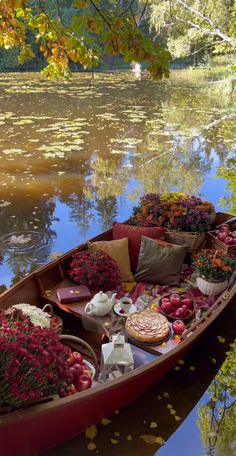 a row boat filled with lots of flowers and pies on the water's edge