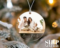 a christmas ornament hanging from a tree with a family photo on the front