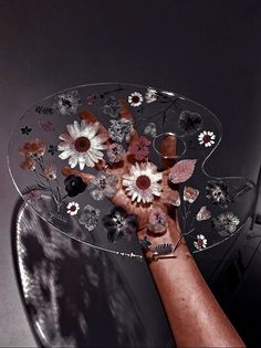 a person holding a glass plate with flowers on it