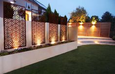 an outdoor garden with lights on the wall and grass in the foreground, next to a house