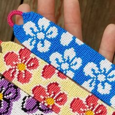 three pieces of cross - stitched fabric are being held by someone's hand