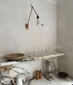 a kitchen with marble counter tops and white walls, an overhead light hangs over the sink