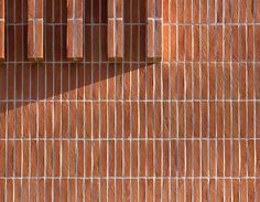 a red brick wall with two windows and a clock on it's side, in front of a building