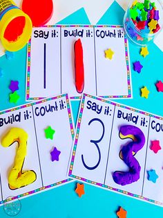 three cards with numbers on them sitting next to confetti cones and glue sticks