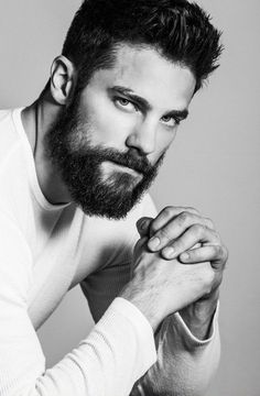 a man with a beard and white shirt is posing for a photo in black and white