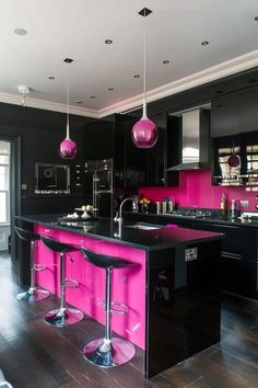 a black and pink kitchen with stools in front of the countertop, sink and refrigerator