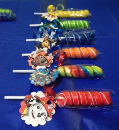 candy lollipops are lined up on a blue tablecloth with cartoon characters