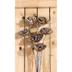 three flowers are hanging on a wooden wall with metal rods and leaves in the center