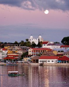 a full moon is seen over the city skyline as boats float on the water in front of it