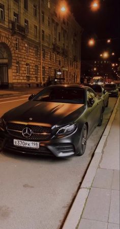 a black car parked on the side of a road next to a building at night