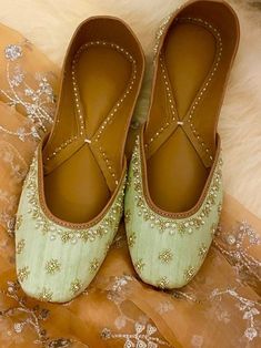 two pairs of green shoes sitting on top of a white furnishing covered floor