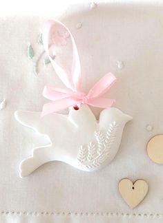 a white bird ornament with a pink bow on it's neck and two hearts