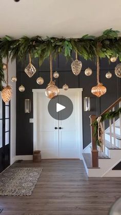 a living room decorated for christmas with ornaments and greenery hanging from the ceiling above