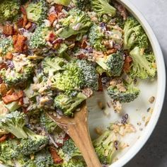 broccoli and bacon casserole in a white bowl with a wooden spoon