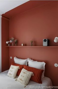 a bedroom with orange walls and white linens on the bed, along with decorative accessories