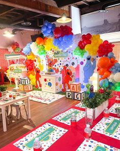 a room filled with lots of colorful balloons and table cloths on top of a wooden floor