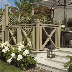 a patio with an umbrella over it and flowers in the foreground, next to some steps