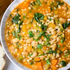 a white bowl filled with soup next to bread