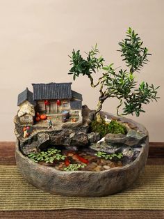 a bonsai tree in a bowl with rocks and plants on the table next to it