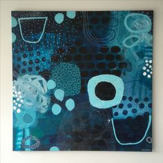 an abstract painting with blue and black circles on the bottom, in front of a white wall