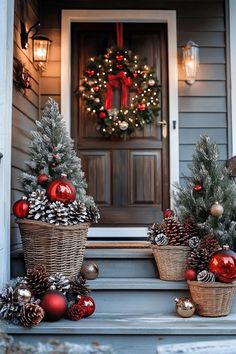 christmas decorations on the front steps of a house with wreaths and pine cones in baskets