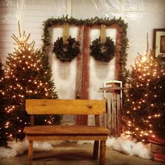 a wooden bench in front of christmas trees with wreaths on the wall behind it