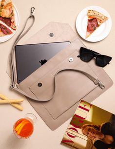 a table topped with plates and glasses next to a laptop computer on top of a bag