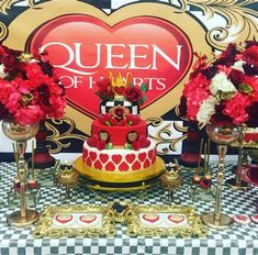 a table topped with a red and white cake next to two vases filled with flowers