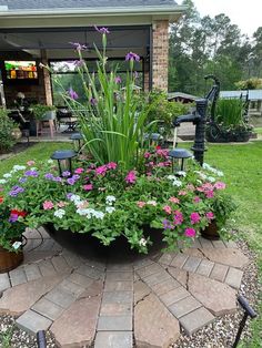 an outdoor garden with flowers and plants in the center, surrounded by brick pavers