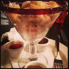 a glass bowl filled with food sitting on top of a table next to sauces