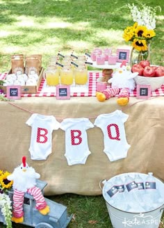 a baby shower is set up on the grass with flowers and apples in buckets