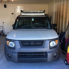 a silver truck parked in a garage next to a surfboard rack and other items