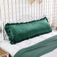 a green pillow sitting on top of a white bed