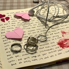 an open book with paper hearts and earphones on it next to other items that have been cut out