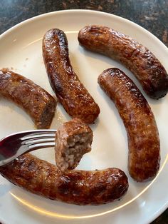 a white plate topped with sausages next to a fork