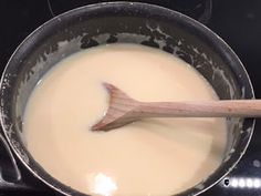 a wooden spoon in a pan on top of an electric stove with liquid being stirred