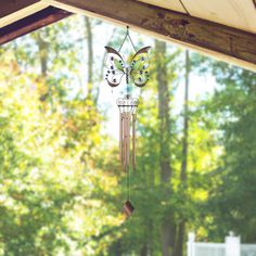 a wind chime hanging from the side of a wooden structure with trees in the background