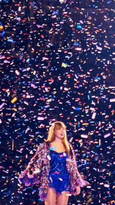 a woman in a blue dress standing on a stage with confetti all around her