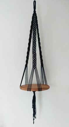 a wooden shelf with black rope hanging from it's sides on a white wall