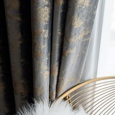 a chair with a white fur on top of it next to a window covered in black and gold curtains