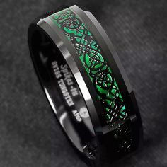 a black and green ring with an intricate design on the inside, inlaided with celtic symbols