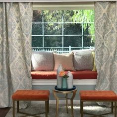 a window seat with two stools in front of it and a vase on the table