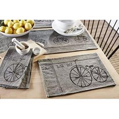 three placemats with bicycles on them are sitting on a table next to bowls of fruit