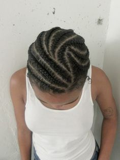 a woman standing in front of a white wall with braids on her hair and wearing a tank top