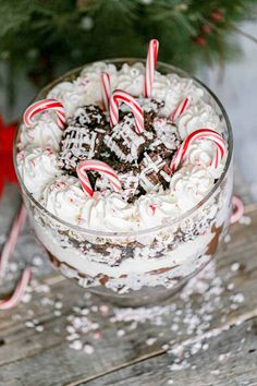 a glass bowl filled with cake and candy canes on top of a wooden table