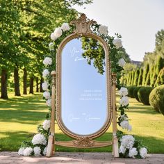 a large mirror sitting on top of a wooden floor next to flowers and greenery