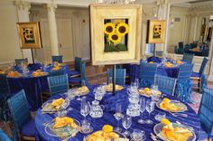 a dining room set up with blue chairs and sunflowers